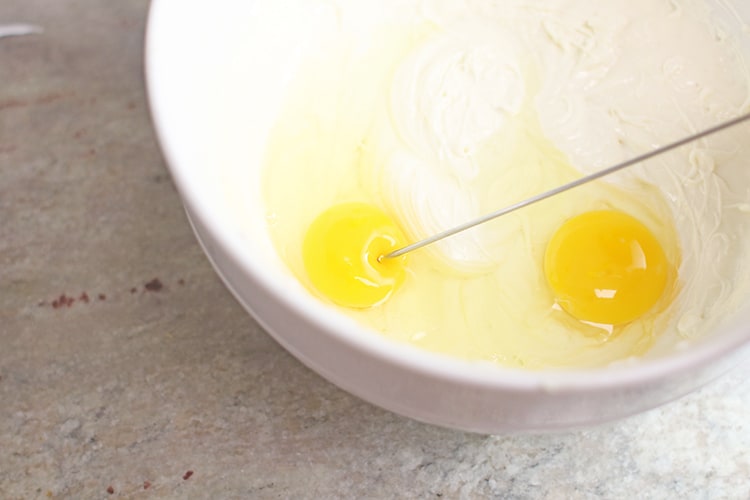 pricking egg yolk in batter for Instant Pot Chocolate Chip Cookie Dough Cheesecake