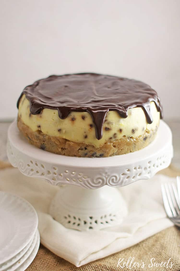 Instant Pot chocolate chip cookie dough cheesecake with ganache on top on a white cake stand