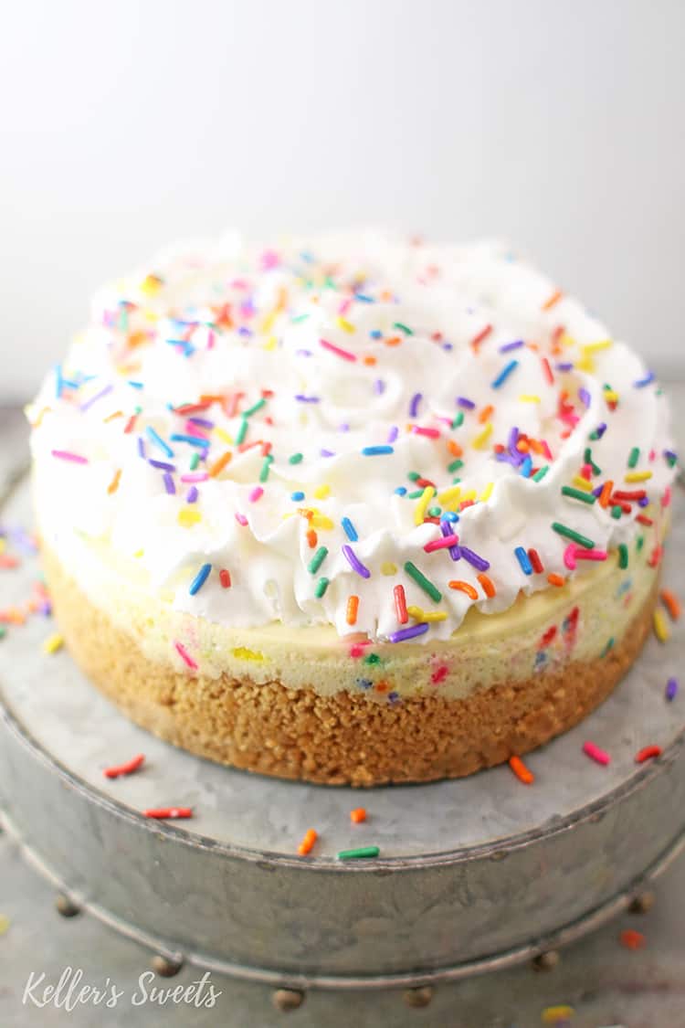Instant Pot Funfetti Cheesecake on Silver Cake Stand with Whipped Cream and Sprinkles
