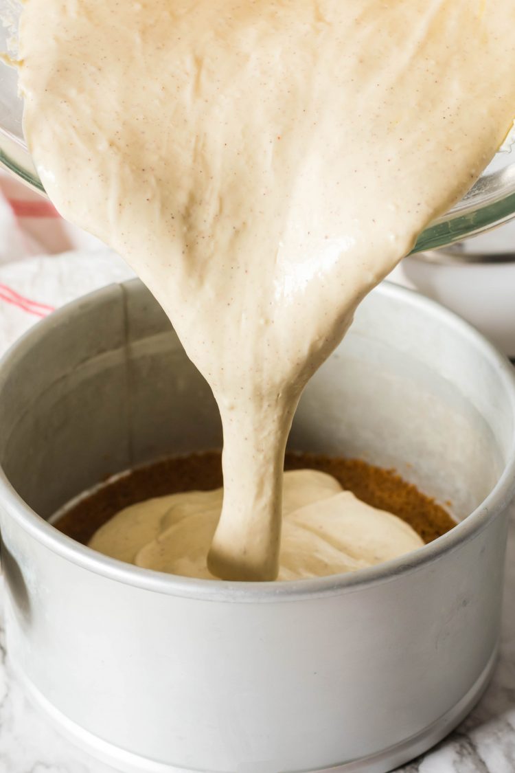 pouring instant pot eggnog cheesecake batter into prepped springform pan