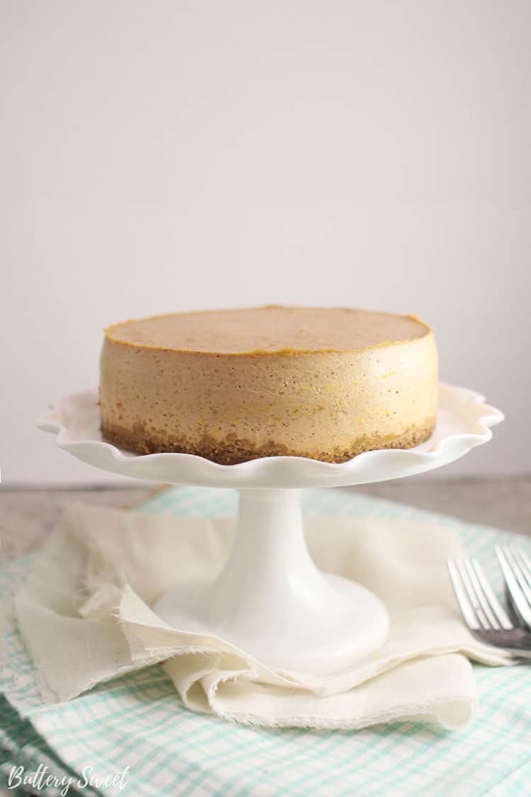 Side view of Instant Pot Pumpkin Pie Cheesecake on a cake stand before caramel sauce