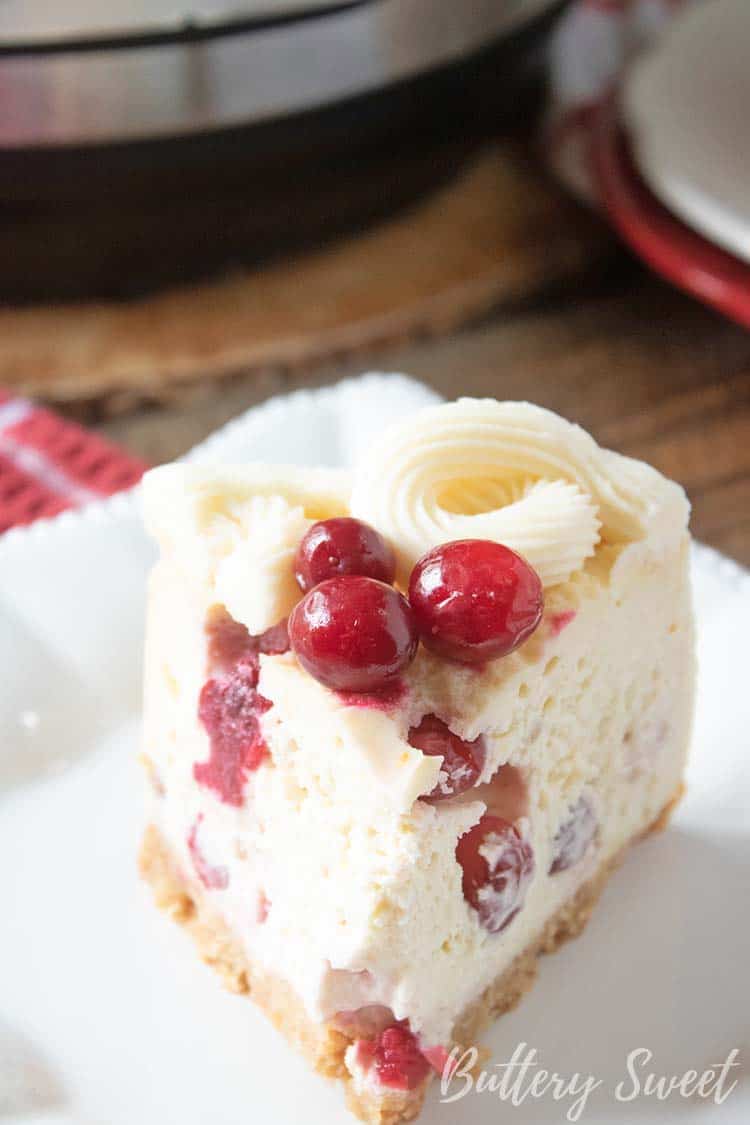 Slice of Instant Pot Cranberry Orange Cheesecake topped with fresh cranberries on a white plate.