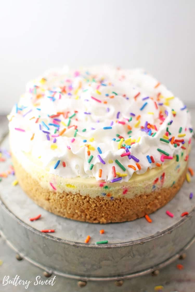 Funfetti cheesecake topped with whipped cream and rainbow sprinkles on top.